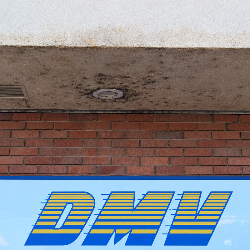 Before: stained, mildewed soffit above a brick wall at a Northern California DMV office
