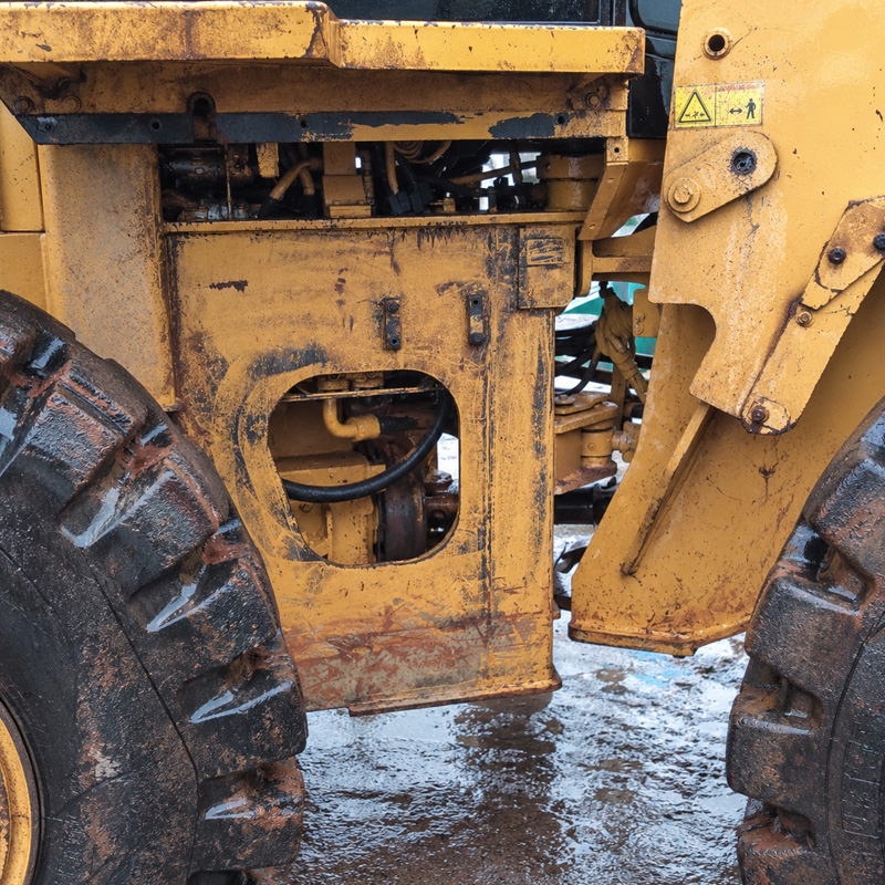 Yellow wheel loader covered in mud, rust and grease before heavy equipment washing